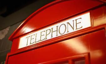 "a red telephone booth with the word "" telephone "" written on it , situated in a city setting" at Le Room Hotel Taoyuan