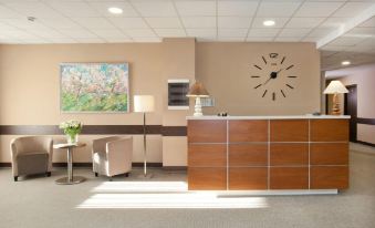 a reception area with a wooden desk , a clock on the wall , and a painting at L'Hotel