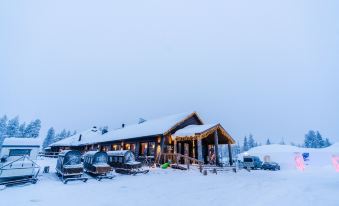 a snow - covered building with a sign , surrounded by trees and cars , on a snowy day at Northern Lights Village