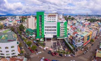 an aerial view of a city with buildings , cars , and a large green building in the center at Tre Xanh Hotel