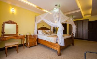 a large bed with a wooden headboard and white canopy is in a room with yellow walls at Rainbow Ruiru Resort