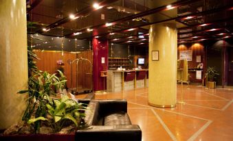 a large , well - lit room with a reception desk and couches , featuring a potted plant on the left at Hotel Diplomatic