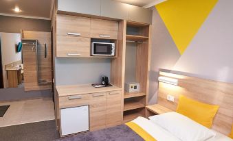 a modern hotel room with a bed , desk , and kitchenette , along with gray and yellow accents at Luna Hotel