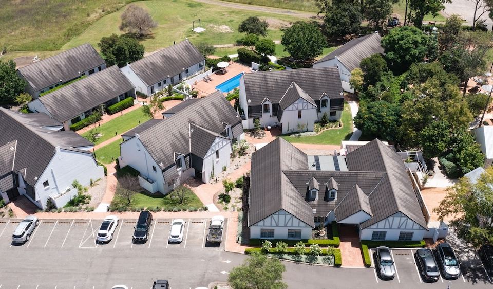 an aerial view of a residential area with multiple houses , a pool , and cars parked in the driveway at Camden Valley Inn