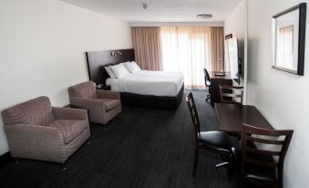 a hotel room with a bed , chairs , and a tv . also a dining table in the room at St Ives Apartments