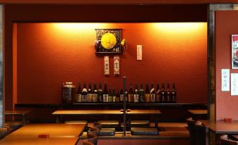 a dining area with a long table and chairs , along with several bottles of liquor on the table at Hotel Wing International Himeji