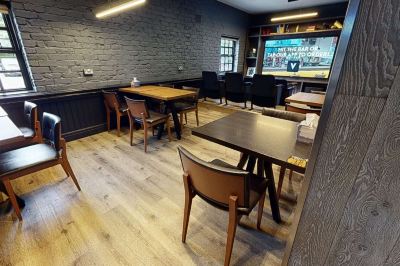 a modern restaurant with wooden tables and chairs , a brick wall , and a television screen at Village Hotel Liverpool