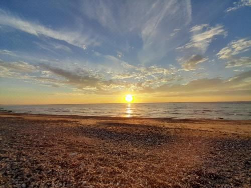 a beautiful sunset over the ocean , with the sun shining brightly in the sky and casting a warm glow on the water at Bord de Mer