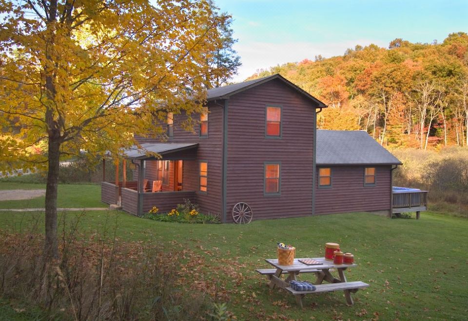 a wooden house surrounded by trees , with a picnic table in front of it for a meal at Opossum Creek Retreat