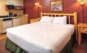 a bed with a white comforter and two white pillows is in a room with red walls at Kohl's Ranch Lodge