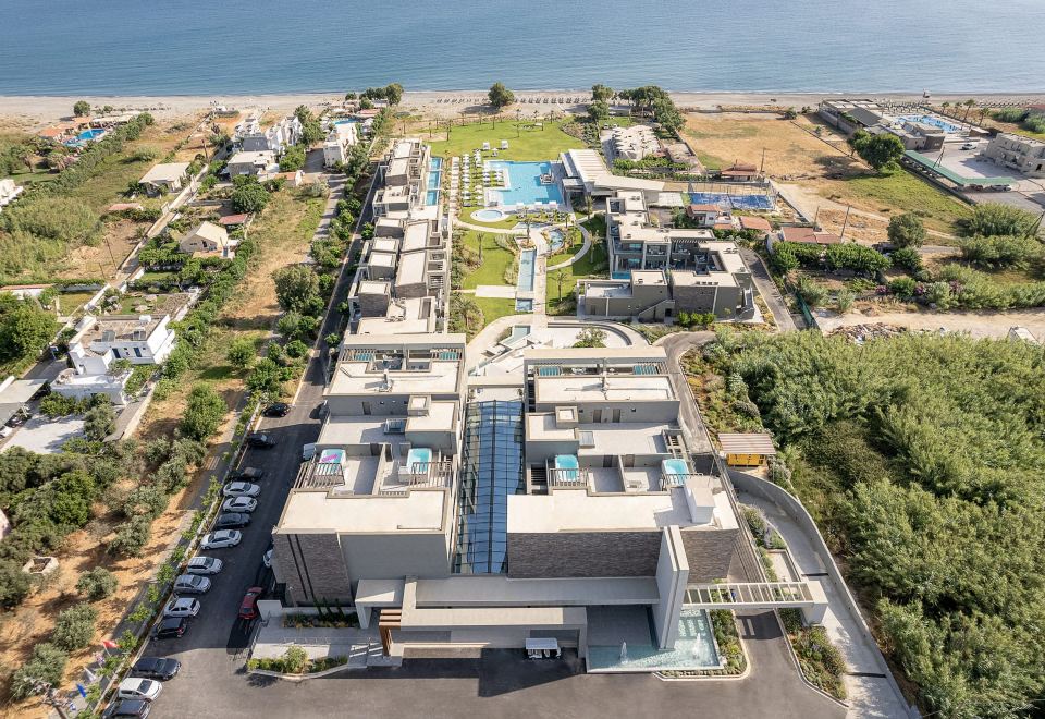 aerial view of a modern apartment complex near the ocean , with a swimming pool in the foreground at Myrion Beach Resort & Spa - Adults Only