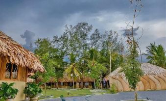 a tropical resort with thatched huts and palm trees , surrounded by lush greenery and dark clouds at Royal Beach