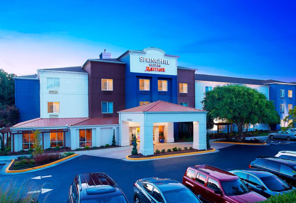 an exterior view of a hotel or motel with multiple buildings , including a parking lot and several cars at SpringHill Suites Atlanta Six Flags