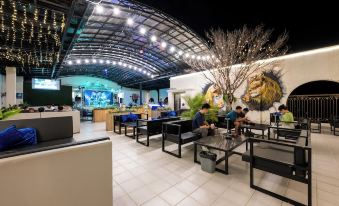 a modern cafe with black furniture , large windows , and a central tree , surrounded by people enjoying their meals at Lbn Asian Hotel