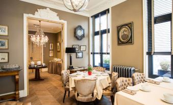 a modern restaurant interior with elegant dining tables , chandeliers , and artwork on the walls , surrounded by comfortable chairs and a chandelier hanging from at Hotel Vendome, BW Signature Collection