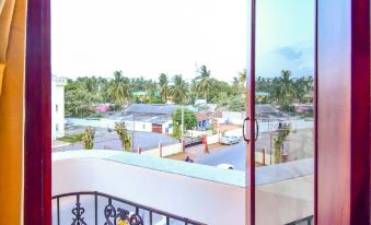 a balcony with a colorful railing and yellow curtains overlooks a cityscape , including a small village at OYO Flagship Hotel Priso