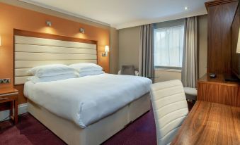 a large bed with white linens is in a room with a desk and chair at The Telford Hotel, Spa & Golf Resort
