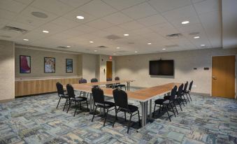 a conference room with a long wooden table , multiple chairs , and a television mounted on the wall at Home2 Suites by Hilton Portland