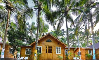 a wooden house surrounded by palm trees , with several lounge chairs placed in front of it at Bluebay Beach Resort