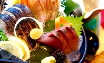 a bowl filled with various types of sushi , including tuna , salmon , and shrimp , placed on a dining table at Hotel Resol Machida