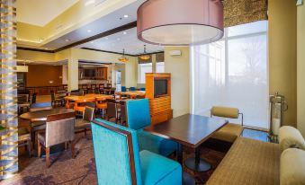 a dining room with multiple tables , chairs , and a large tv mounted on the wall at Hilton Garden Inn Kankakee