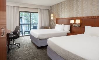 a hotel room with two beds , a desk , and a sliding glass door leading to a balcony at Courtyard Chicago Wood Dale / Itasca