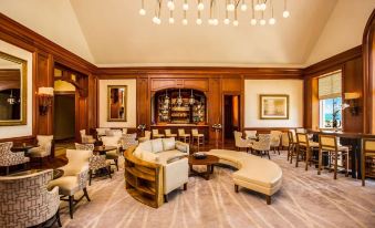 adjacent living room with comfortable seating and tables, complemented by a bar area at The Ritz-Carlton Golf & Spa Resort, Rose Hall, Jamaica