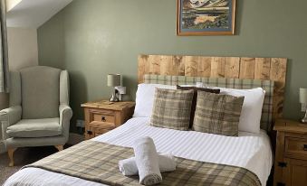 a cozy bedroom with a large bed , two chairs , and a painting on the wall at Number 19 Guest House - 4 Miles from Barrow in Furness - 1 Mile from Safari Zoo
