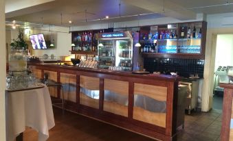 a bar with a wooden counter and several bottles of liquor on display behind it at Grand Pacific Hotel