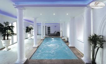 an indoor pool with a blue and white color scheme , surrounded by white columns and a spa area at Le Continental