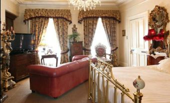 a luxurious bedroom with a large bed , red couches , and a crystal chandelier hanging from the ceiling at Charlemont House