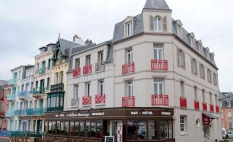 a white building with red balconies and a brown awning is located on a street at Bellevue Beaurivage