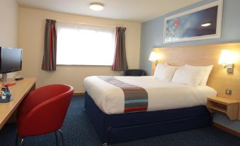 a hotel room with a large bed , two chairs , and a window , all decorated in a modern style at Travelodge Glenrothes