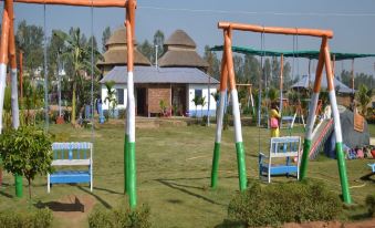 On an overcast day at the park, there is a playground with swings and slides at Hotel Banalata