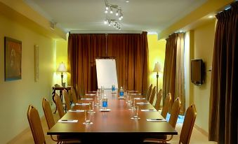 a conference room with a long wooden table , chairs , and a whiteboard , set up for a meeting at Hotel Brossard