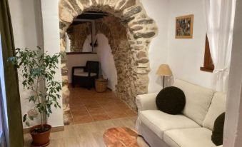 a living room with a white couch , wooden coffee table , and a stone archway leading to another room at Apartamentos Turisticos "El Refugio"