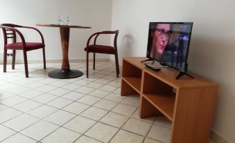 a television is sitting on a small wooden stand in a room with two chairs and a table at Hotel 28