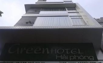 a tall building with a green hotel sign on the side , located in an urban area at Green Hotel