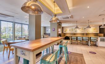 a modern , well - lit restaurant with wooden tables and chairs , a bar area , and pendant lights at Premier Inn Bangor (Northern Ireland)