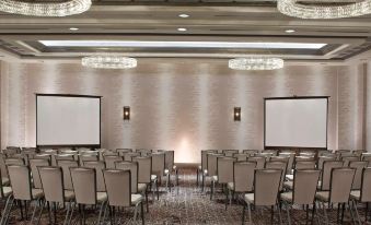 a conference room with rows of chairs arranged in a semicircle , and a podium at the front of the room at Rochester Airport Marriott