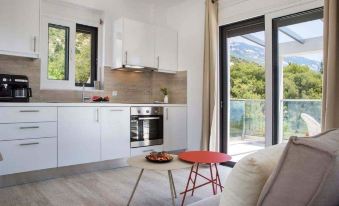 a modern kitchen with white cabinets , a dining area , and a red coffee table near a sliding glass door at Lygies Studios