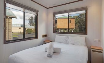 a clean and well - organized bedroom with a white bed , multiple pillows , and a window view at Discovery Parks - Eden