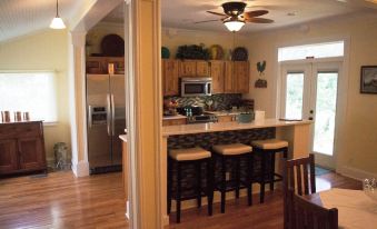 a kitchen with wooden cabinets , a dining area with stools , and an open door leading to the outside at Dolan House B&B
