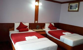 a hotel room with two beds , each bed having red and white linens , accompanied by wooden headboards at Rawanda Resort