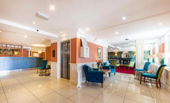 a modern hotel lobby with a reception desk , seating area , and an elevator in the background at The Beaches Hotel