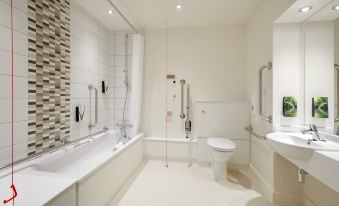 a modern bathroom with white walls , a bathtub , and shower , as well as a toilet and sink at Premier Inn Caerphilly (Corbetts Lane)