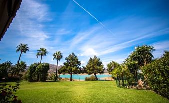 a grassy field with trees and a body of water in the background , creating a picturesque scene at B Bou Hotel la Vinuela & Spa