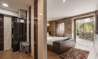 a modern bedroom with a large bed , a couch , and a door leading to a balcony at Casa da Fonte