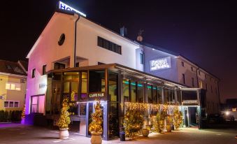 "a large white building with a sign that says "" hotel "" and christmas trees in front of it" at Royal Airport Hotel