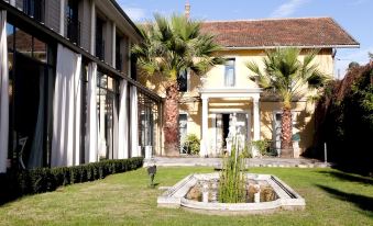 a courtyard with a fountain and palm trees in front of a yellow building , creating a picturesque setting at La Maison Navarre